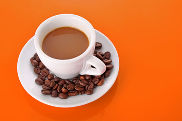 Small white cup of coffee with coffee grain on orange background