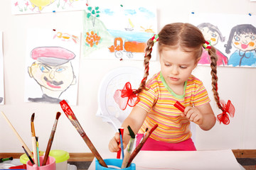 Child with picture and brush in playroom.