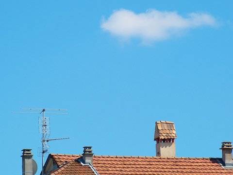 Toit, cheminée, antenne et ciel bleu