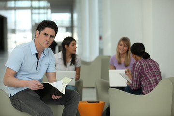 Jeune homme assis près d'une groupe d'étudiantes