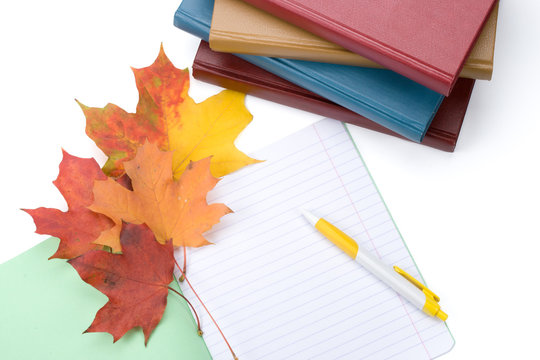 Pile of books, writing-book, pen and autumn leaves