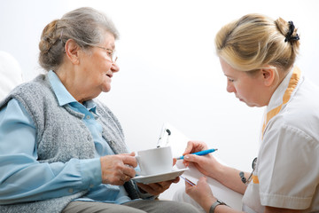 Senior woman is visited by her doctor or caregiver - obrazy, fototapety, plakaty