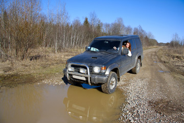 Young woman behind rudder of offroad car on dirt road