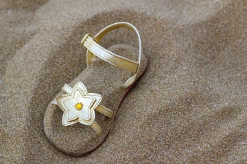 golden star sandal buried in summer beach sand