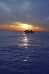 sunset sunrise with fishing boat in horizon