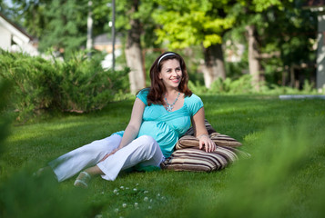 Beautiful pregnant woman laying on grass