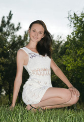 Cute young female sitting on grass field at the park