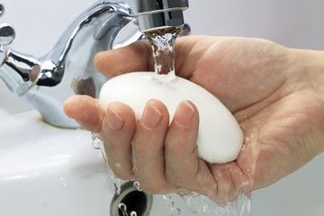 hands with soap under a stream of water from the stop-cock