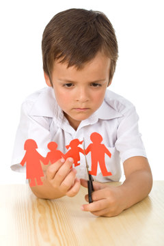Sad kid cutting up paper people family - divorce concept
