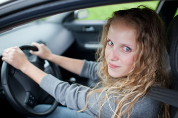 Fototapeta na wymiar Pretty young woman driving her new car