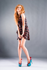 Beautiful red-haired girl on grey background