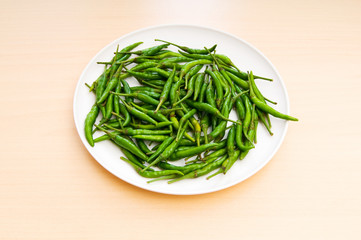 Hot peppers in the plate on wooden table