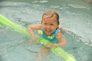 Adorable little blond girl smiling in the pool