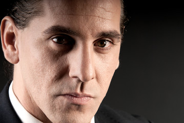 Adult businessman closeup portrait on dark background.