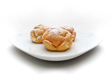 Three profiteroles on a plate, isolated, white background