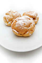 Three profiteroles on a plate, isolated, white background