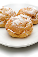 Three profiteroles on a plate, isolated, white background