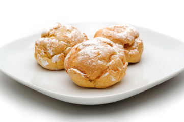 Three profiteroles on a plate, isolated, white background