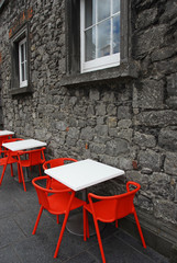 Rote Stuehle vor historischem Gemaeuer in Kilkenny/Irland