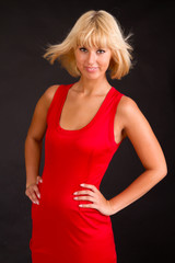 Charming lady in red evening dress, on black background.