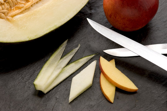 two blades, an apple, honeydew melon and slices of fruits