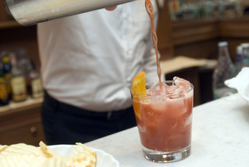 Barkeeper spills drink from shaker into glass