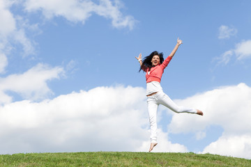 pretty young woman jumping on green grass