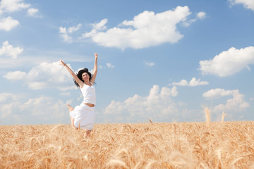 Naklejka na ściany i meble Happy woman jumping in golden wheat