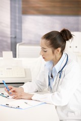Female doctor writing at desk