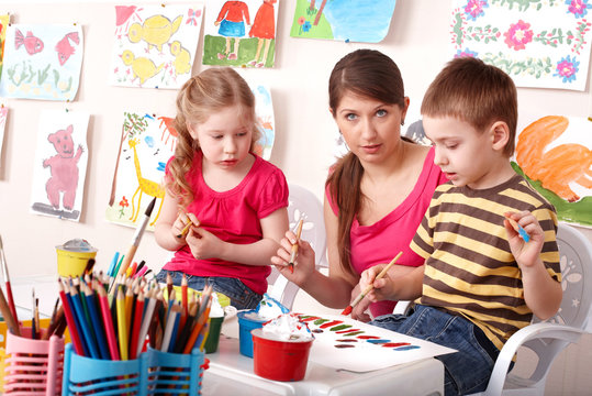Children  painting with teacher in school.