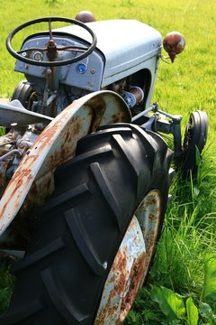 Rostiger Oldtimer Traktor auf einer grünen Wiese