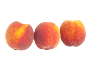 Closeup of three peaches in a row isolated on white