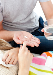 Obraz na płótnie Canvas Close-up of young man giving pills to his morbid girlfriend