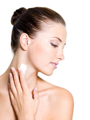 woman applying moisturizer cream on shoulder