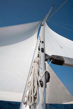 Yacht sail and mast with blue cloudless sky in the background