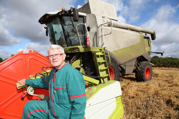 Farmer standing by harvester in wheat field