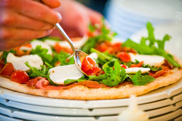 preparing pizza in a kitchen and adding ingredients