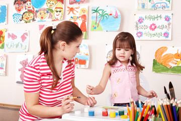 Fototapeta premium Child with teacher draw paints in play room.