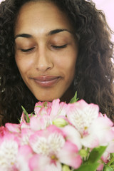 Female smelling flowers with eyes closed