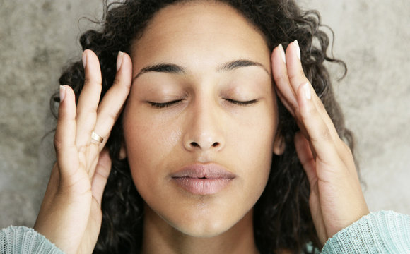 Young female with headache and massaging her temples
