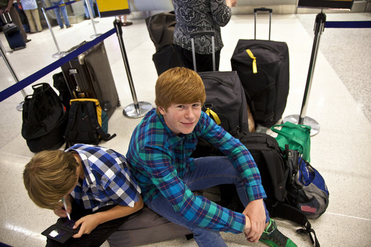 boys is sitting on the baggage waiting for check in