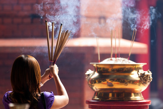 woman holding incense sticks in chinese temple