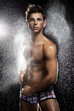 Muscular young man having shower