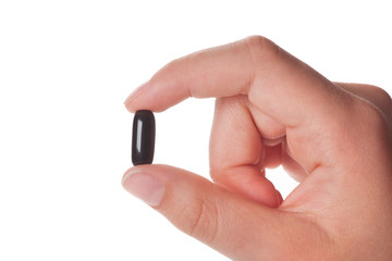 female hand holding a black capsule, isolated