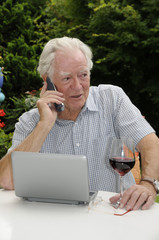 Rentner mit Handy, Netbook und Rotwein