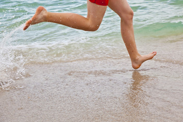 feet of boy running along the beach
