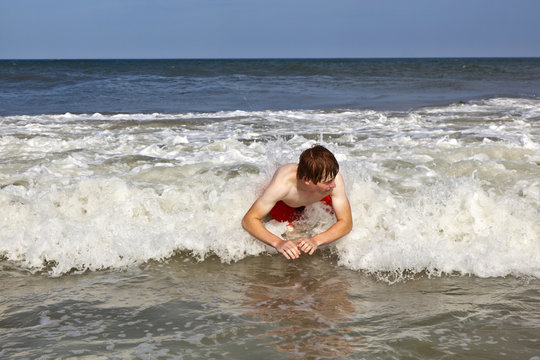 young boy is body surfing in the waves