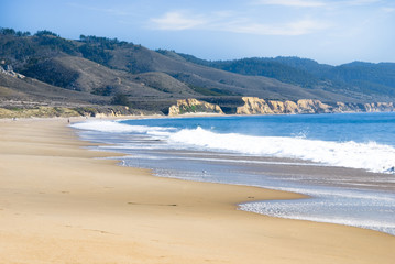 Fototapeta na wymiar Blue bay with sandy beach and surf