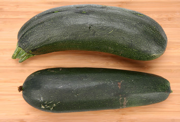 Two zucchinis on a chopping board on white background