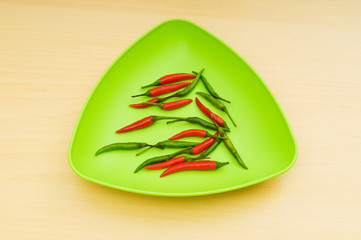 Hot peppers in the plate on wooden table